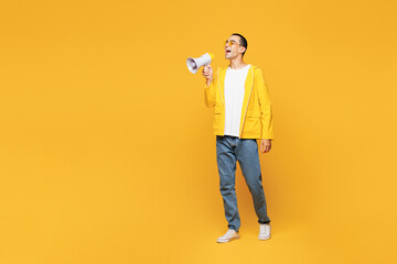 Full body young middle eastern man wears raincoat casual clothes hold in hand megaphone scream announces discounts sale Hurry up isolated on plain yellow orange background studio. Lifestyle concept.