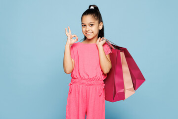 Little smiling fun kid girl 9-10 years old wear pink clothes hold in hand paper package bags after...