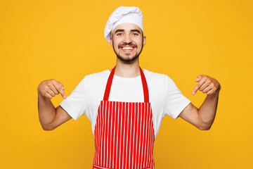 Young happy housewife housekeeper chef cook baker man wear red apron toque hat point index finger...