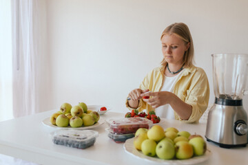 Caucasian woman preparing homemade fruit leather, slicing fresh fruit in her kitchen for a healthy...