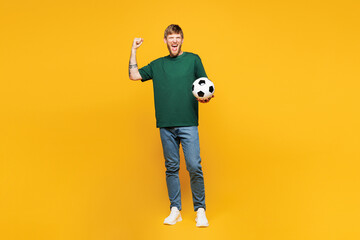 Full body young happy man fan wear basic green t-shirt cheer up support football sport team hold in...