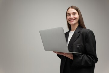 Young professional smiling while holding a laptop in a modern setting, showcasing confidence and...