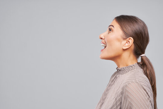 Side profile of smiling woman looking up with open mouth in studio