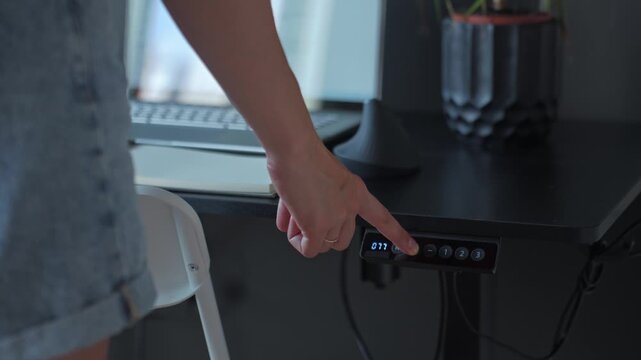 Woman pressing control panel to change height of standing desk