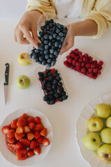 Middle-aged woman preparing homemade fruit leather, slicing fresh fruit in her kitchen for a healthy snack. Part of a series on organic treats and natural living. User-generated content