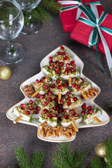 Appetizer of Brie cheese with pomegranate and nuts in Christmas tree-shaped plate