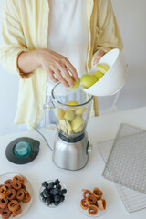 Caucasian woman preparing homemade fruit leather, slicing fresh fruit in her kitchen for a healthy snack. Part of a series on organic treats and natural living
