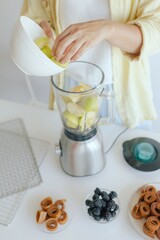 Caucasian woman preparing homemade fruit leather, slicing fresh fruit in her kitchen for a healthy snack. Part of a series on organic treats and natural living.