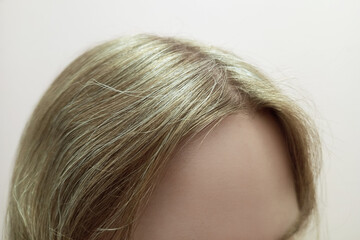 Gray hair on the head of a Caucasian blonde, close-up view of the top of the head.