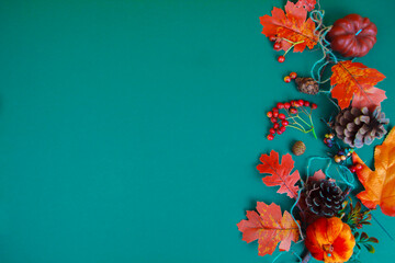 Yellow tree leaves lie next to cones and red berries on a green background. Space for text.