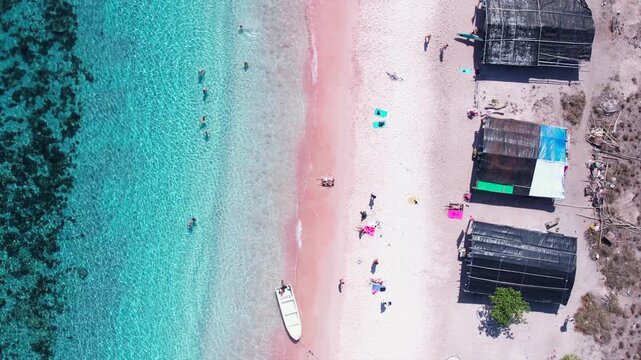 Aerial drone view of Pink Beach with turquoise water, in Indonesia, with tourists relaxing. Komodo National Park