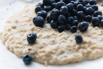 Hot sweet oatmeal in a bowl with blueberries - a hearty delicious breakfast