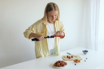 Middle-aged woman preparing homemade fruit leather, slicing fresh fruit in her kitchen for a...