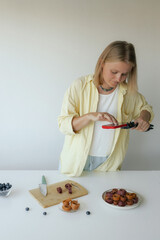 Middle-aged woman preparing homemade fruit leather, slicing fresh fruit in her kitchen for a...