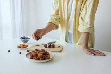 Caucasian woman preparing homemade fruit leather, slicing fresh fruit in her kitchen for a healthy snack. Part of a series on organic treats and natural living
