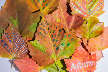 Painted fall leaves on a white wooden background. Child creativity and zero waste concept.
