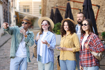 Guide with microphone and group of tourists on city street during excursion
