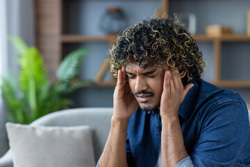 Individual experiencing discomfort while indoors, holding head, expressing stress or headache.