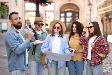 Guide with microphone and group of tourists on city street during excursion