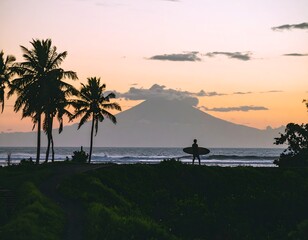Silhouetted surfer at sunset, gazing at a distant, hazy volcano