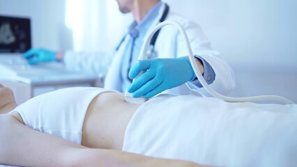Doctor man wearing a blue medical gloves using an ultrasound equipment on a female patient lying...