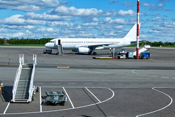 Commercial airplane parked on airport tarmac with boarding stairs, jet engines, fuselage. Aviation...