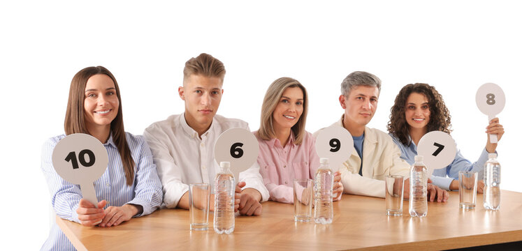 Panel of judges voting with score signs at table on white background