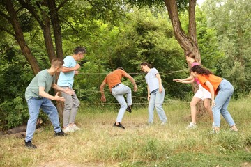 Team building. Group of happy people playing spider web game outdoors