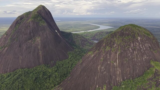 Aerial view of the majestic Cerros de Mavicure rising from the verdant Amazon rainforest, with a winding river snaking through the landscape, Cerros Mavicure, Colombia.