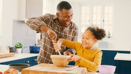 Family Shot With Father And Daughter Baking At Home In Kitchen Mixing Ingredients In Bowl