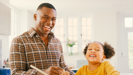 Father And Daughter Baking At Home In Kitchen With Cake Mixture On Their Noses
