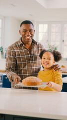 Portrait Of Proud Father And Daughter At Home In Kitchen With Homemade Cake They Have Baked Together