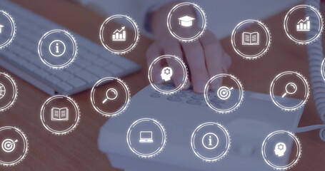 Pressing hand in office top wearing wristwatch dialing telephone near keyboard with digital icons
