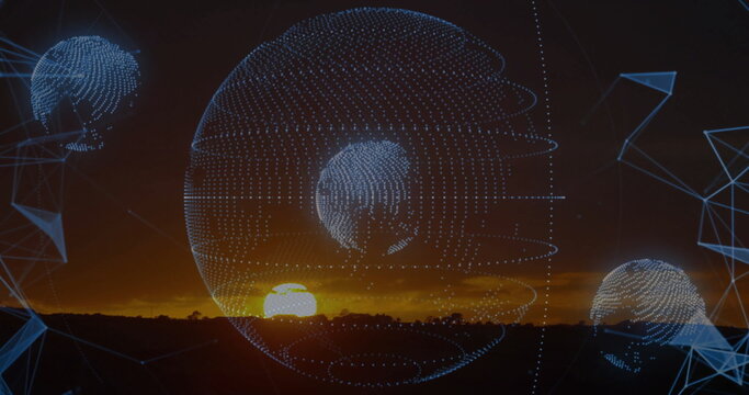 Fototapeta Showing central and smaller wireframe globes hovering over plain at sunset, with blue mesh shapes