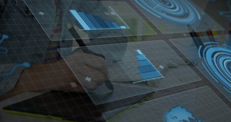 Hand holding stylus pen drawing visualizations on office desk, with coffee mug and floating charts