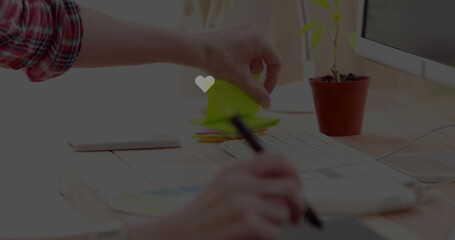 Reaching hand in plaid shirt placing sticky notes on office desk, with drawing tablet and stylus