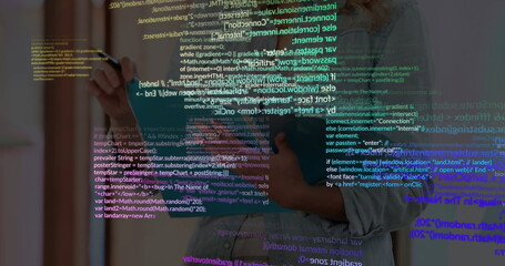 Developer wearing denim shirt writing code on glass panel in office with marker pen, copy space