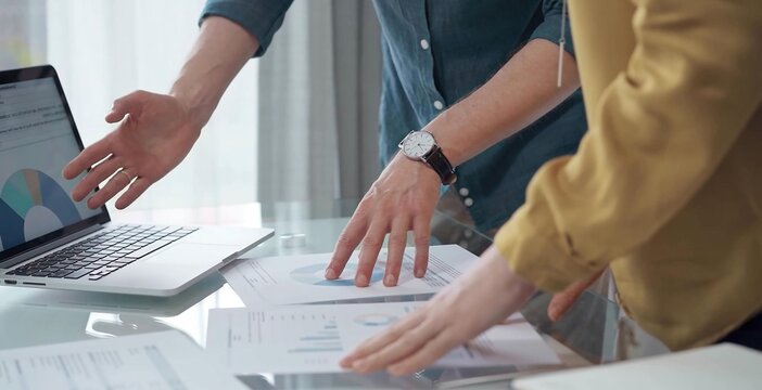 Business people, professionals analyzing financial charts and data on a desk while standing and using laptop computer in office