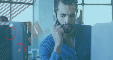 Middle Eastern man talking on smartphone and analyzing laptop charts at office desk, copy space