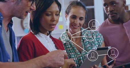 Collaborating four coworkers viewing network diagram on tablet at office, with smartphone icons
