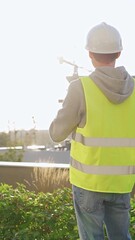 Man engineer with white helmet and safety vest is using tablet computer while inspecting a...