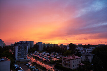 Fototapeta premium Panoramic View of an Urban Area at Sunset with Colorful Sky, Residential Buildings, and Busy Parking Lots