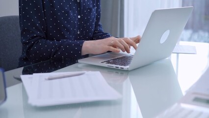 A female accountant or businesswoman is typing on laptop computer on glass desk in the office....
