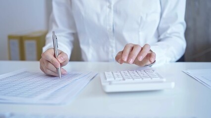 Businesswoman with white blues calculating finance with calculator and taking notes at office table. Audit and taxes