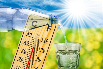 Ein Thermometer zeigt Hitze mit hoher Temperatur und symbolisch eine Wasserflasche mit Glas zum...