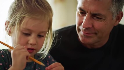 young caucasian girl focused on writing with pencil as supportive father observes. concept of childhood education, learning and mentorship, family bonding and support. parenting, adhd awareness month.