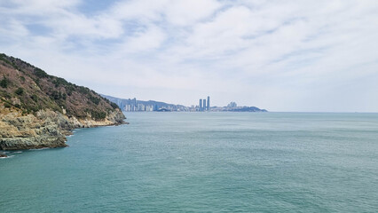 
 Rocky coastline with cliffs and sparse vegetation, turquoise sea with small waves crashing...