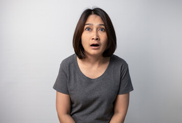 Asian woman standing isolated on grey background big eye surprised wow open mouth and shocked face...