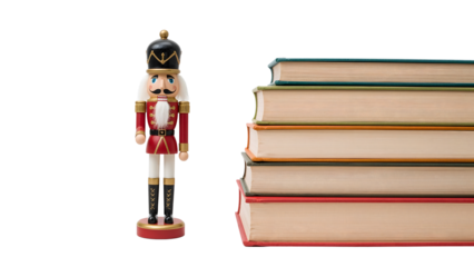 Wooden nutcracker doll standing beside a stack of books isolated on the transparent background, holiday decorations and education theme