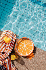 Poolrand mit orangen, sommerlichen Requisiten